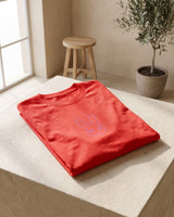 Camiseta SOBETEO SPIDER roja doblada sobre una mesa de madera, vista por la espalda